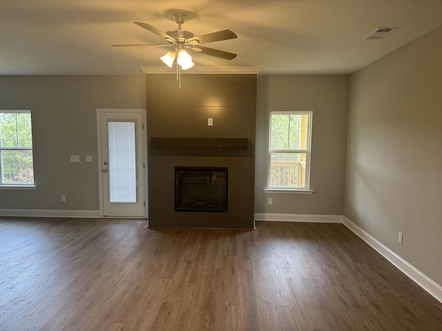 unfurnished living room with visible vents, a ceiling fan, dark wood-type flooring, baseboards, and a large fireplace