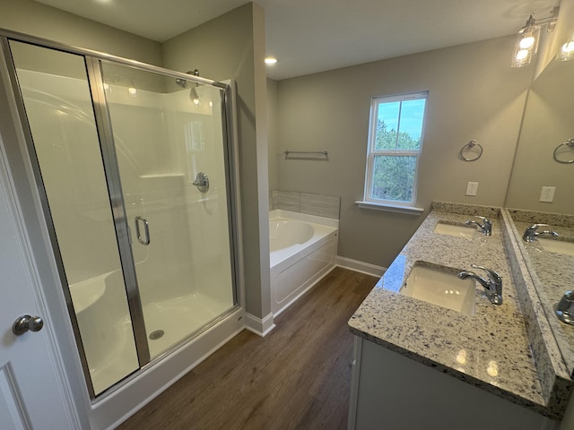 full bathroom with a sink, baseboards, wood finished floors, a shower stall, and a garden tub
