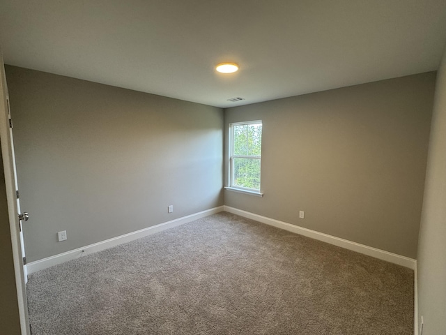 spare room with carpet, visible vents, and baseboards