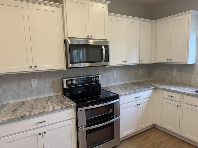kitchen with backsplash, appliances with stainless steel finishes, light stone counters, and white cabinets