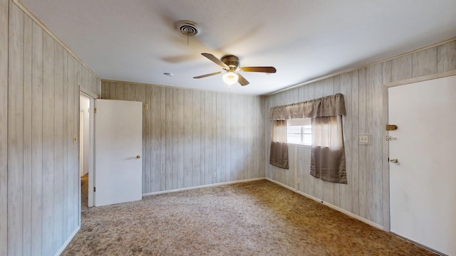 carpeted spare room featuring visible vents, baseboards, and a ceiling fan