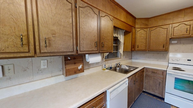 kitchen featuring brown cabinets, a sink, white appliances, crown molding, and light countertops