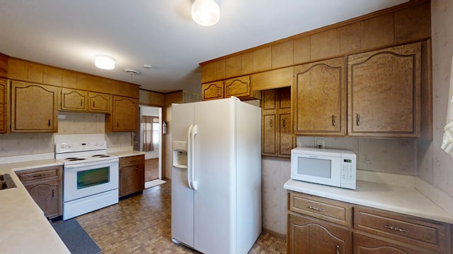 kitchen featuring tile patterned floors, brown cabinets, white appliances, and light countertops