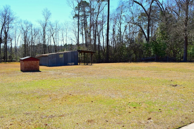 view of yard with an outbuilding and a view of trees