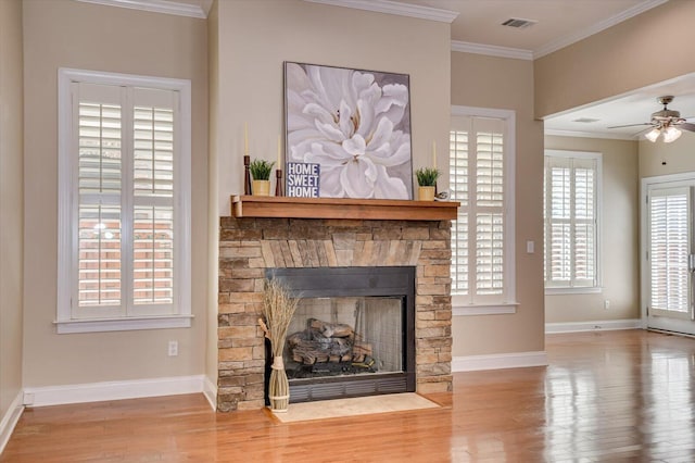 living room featuring visible vents, baseboards, a fireplace with flush hearth, ornamental molding, and wood finished floors