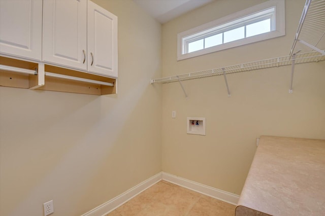 clothes washing area with hookup for a washing machine, cabinet space, and baseboards