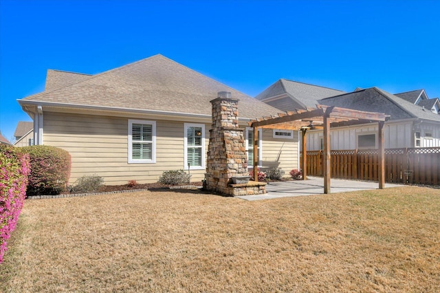 rear view of property featuring a pergola, fence, a yard, roof with shingles, and a patio area