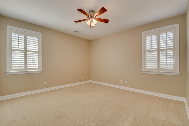 carpeted empty room with visible vents, baseboards, and a ceiling fan