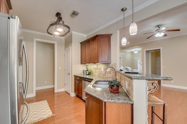 kitchen featuring visible vents, brown cabinets, a peninsula, stainless steel appliances, and a sink