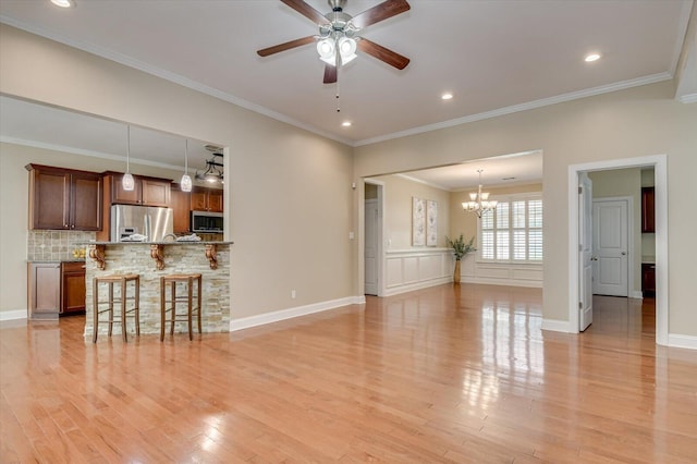 living area with light wood-type flooring, baseboards, crown molding, and ceiling fan with notable chandelier