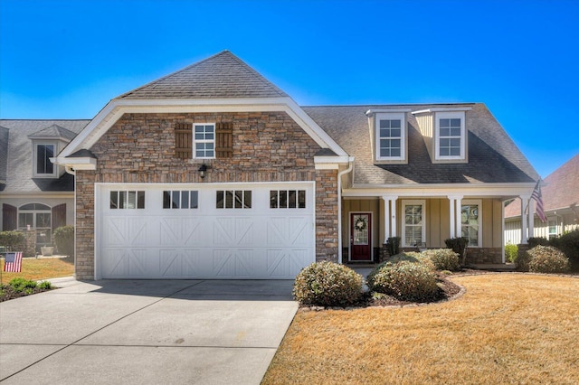 view of front of house with an attached garage, stone siding, driveway, and roof with shingles