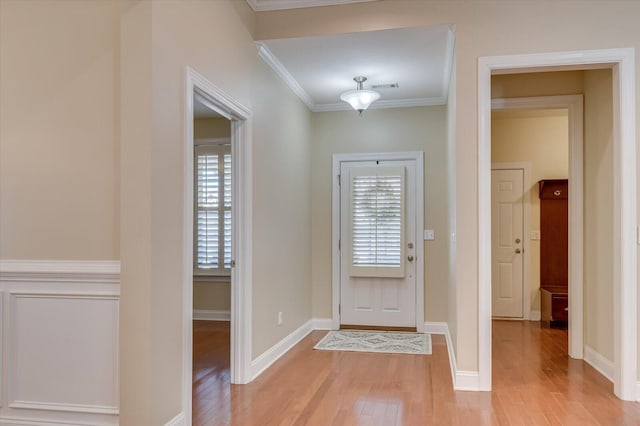 entrance foyer with visible vents, baseboards, light wood-style floors, and ornamental molding