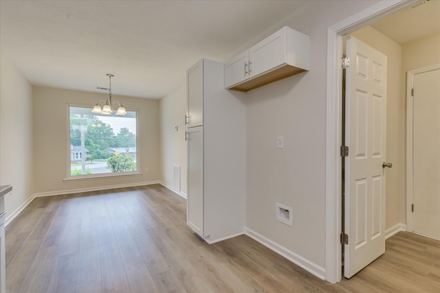 unfurnished dining area with light wood finished floors, a chandelier, and baseboards