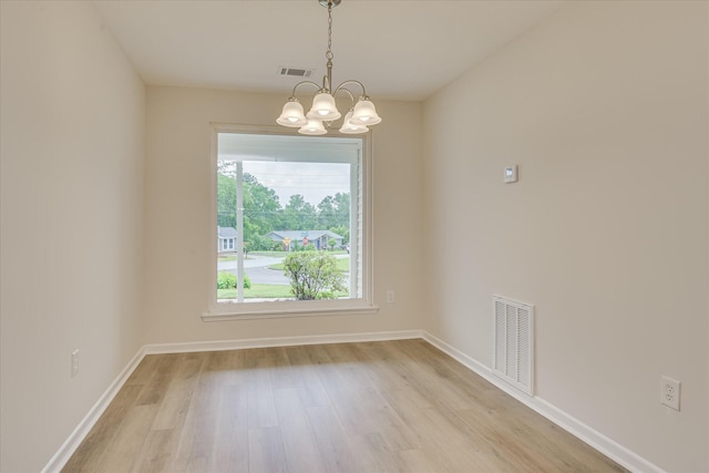 unfurnished dining area with a chandelier, light wood-style flooring, and baseboards