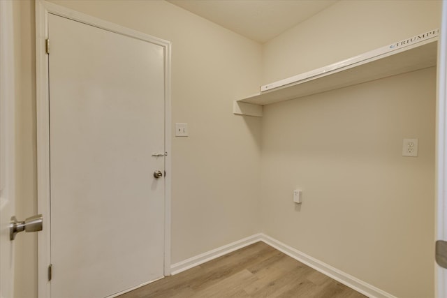 laundry area featuring light wood-style flooring and baseboards