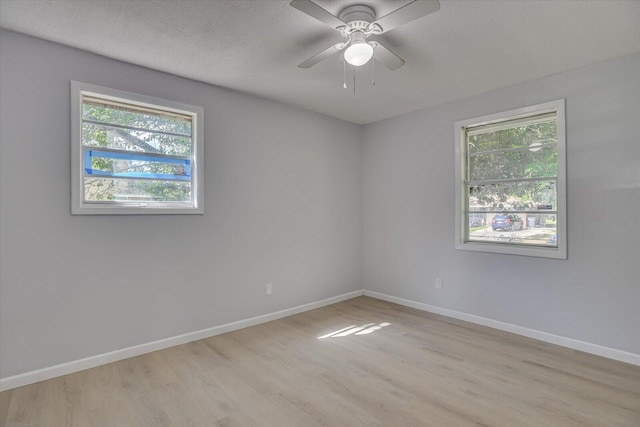 empty room with ceiling fan, light wood-type flooring, and a textured ceiling