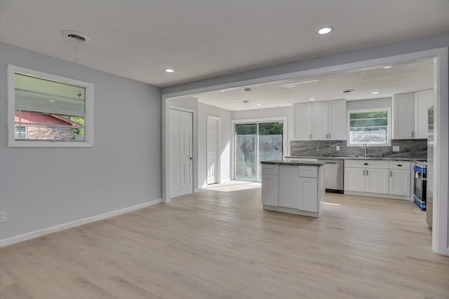 kitchen with white cabinets, appliances with stainless steel finishes, and light hardwood / wood-style flooring