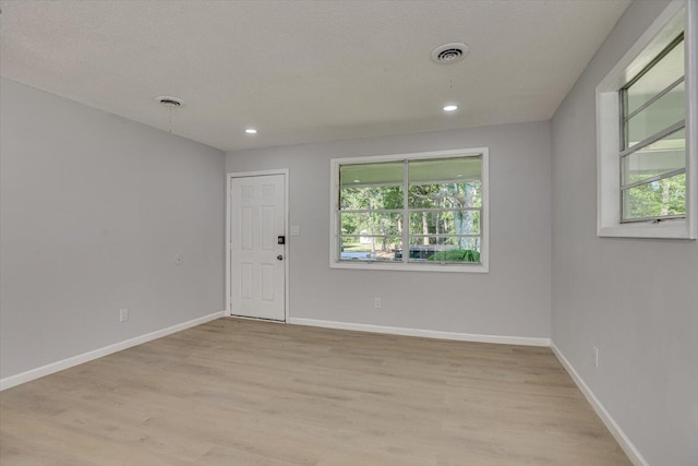 unfurnished room featuring light wood-type flooring and a textured ceiling