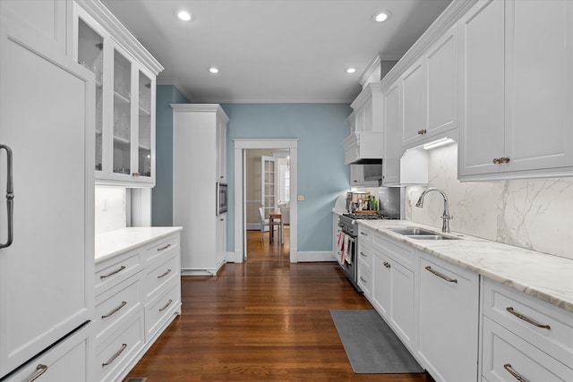 kitchen with white cabinets, tasteful backsplash, high end range, and a sink