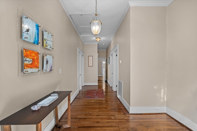 corridor featuring crown molding, visible vents, baseboards, and wood finished floors