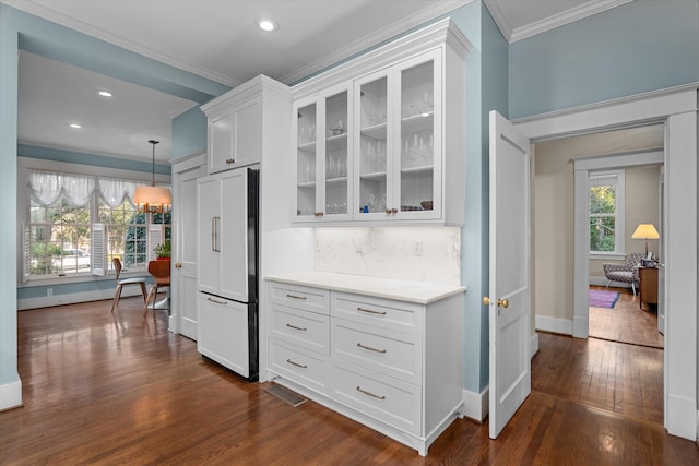 kitchen with paneled fridge, white cabinets, dark wood-style floors, glass insert cabinets, and crown molding