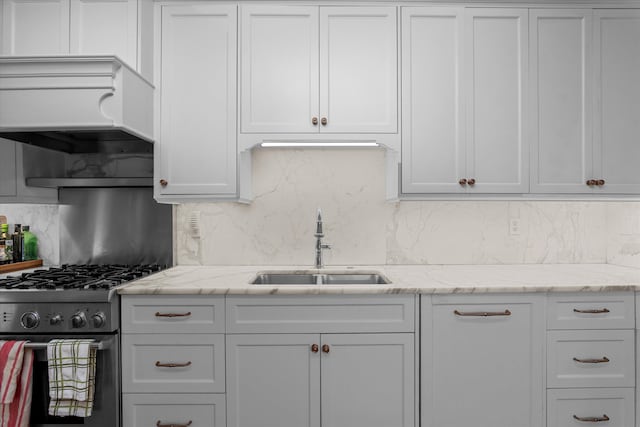 kitchen featuring light stone counters, gas stove, a sink, and backsplash