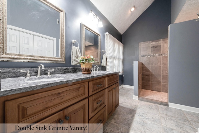 bathroom with tiled shower, vanity, and vaulted ceiling