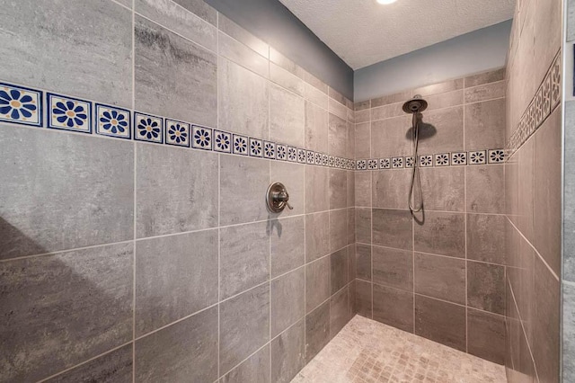 bathroom featuring a textured ceiling and tiled shower