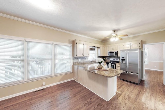 kitchen featuring appliances with stainless steel finishes, light stone counters, ornamental molding, light hardwood / wood-style floors, and kitchen peninsula