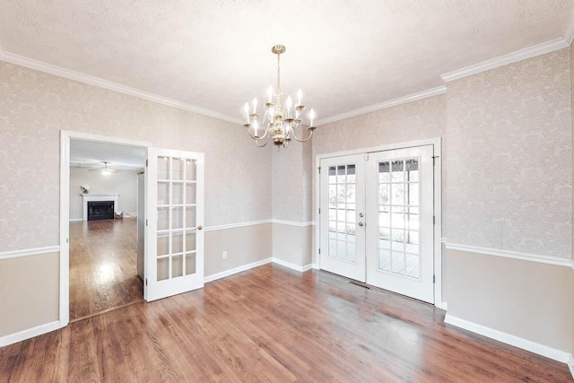 unfurnished dining area with crown molding, wood-type flooring, a textured ceiling, and french doors