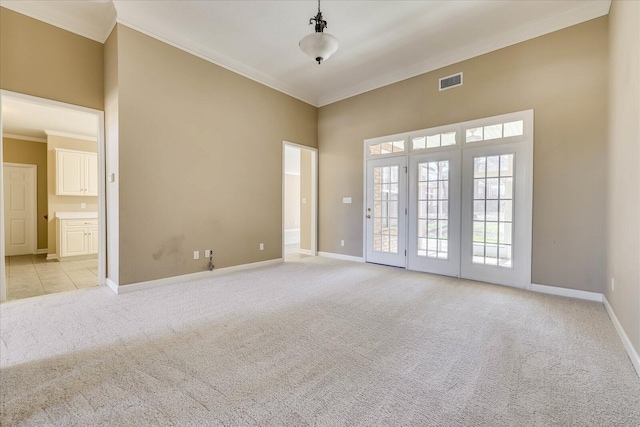 spare room featuring light carpet, ornamental molding, visible vents, and baseboards