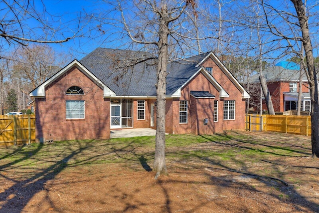 view of front of house featuring a front yard, a fenced backyard, brick siding, and a patio