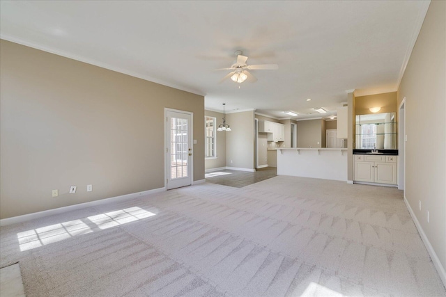 unfurnished living room featuring baseboards, ceiling fan with notable chandelier, ornamental molding, and light colored carpet