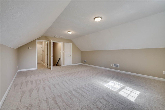 bonus room featuring baseboards, visible vents, a textured ceiling, and light colored carpet