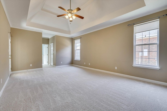 unfurnished room with ornamental molding, a raised ceiling, and baseboards