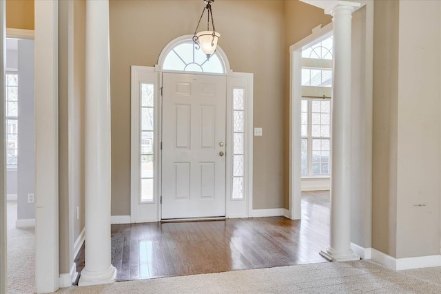 entrance foyer featuring baseboards, ornate columns, and wood finished floors