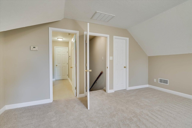 additional living space featuring lofted ceiling, visible vents, and light colored carpet