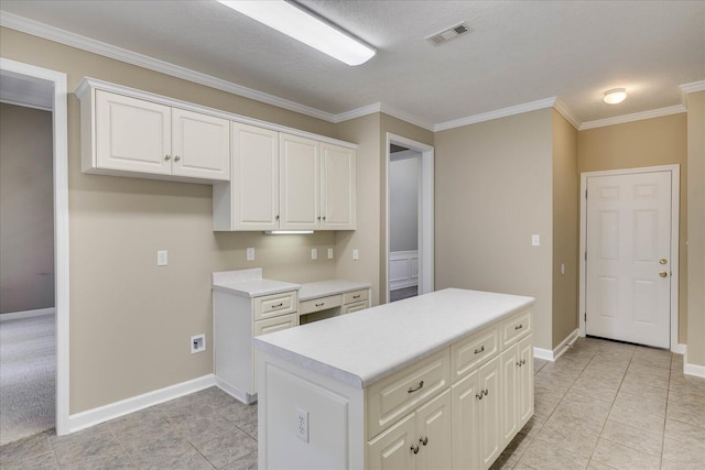 kitchen with visible vents, white cabinetry, light countertops, ornamental molding, and a center island