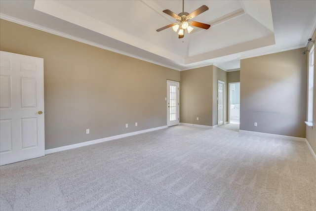 unfurnished room featuring crown molding, a tray ceiling, light carpet, and baseboards