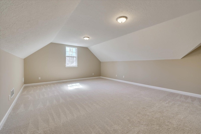 additional living space with light carpet, a textured ceiling, lofted ceiling, and visible vents