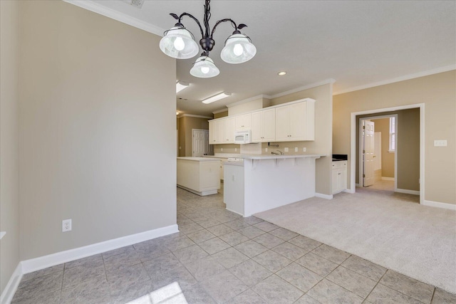 kitchen with white cabinets, pendant lighting, light countertops, and crown molding