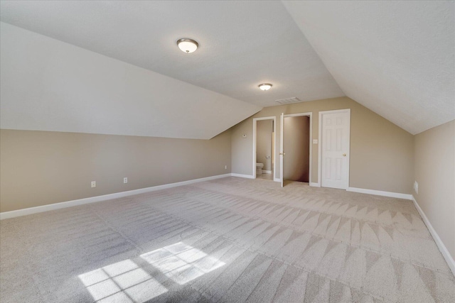 bonus room with light carpet, vaulted ceiling, visible vents, and baseboards