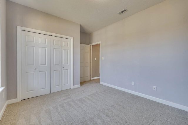 unfurnished bedroom featuring light carpet, baseboards, visible vents, and a closet