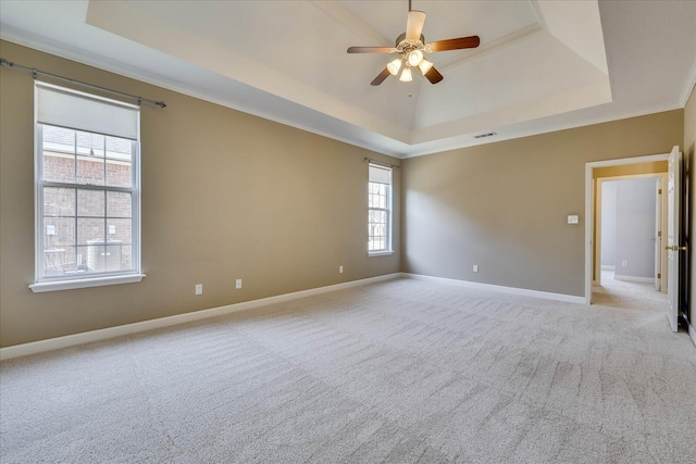 spare room with ceiling fan, light carpet, visible vents, baseboards, and a tray ceiling