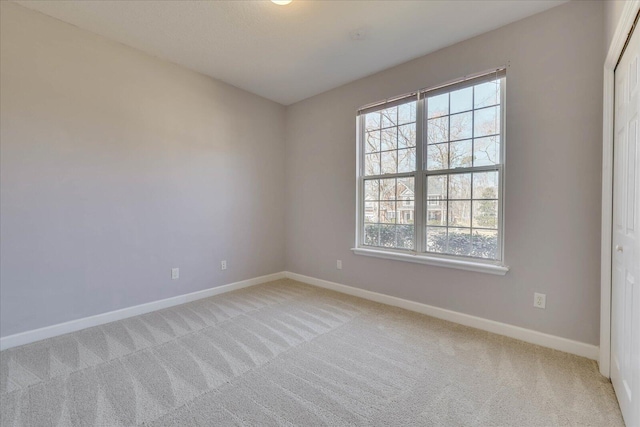 unfurnished room featuring baseboards and light colored carpet