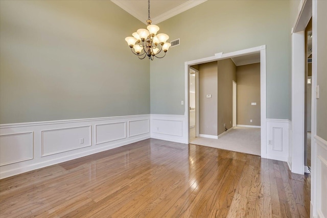 unfurnished room with light wood-style flooring, visible vents, a chandelier, and crown molding