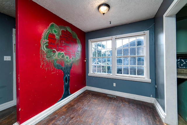 empty room with a textured ceiling and dark hardwood / wood-style flooring