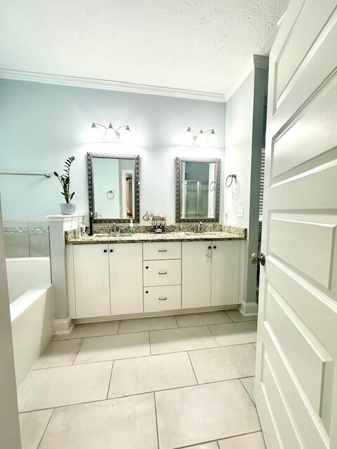 bathroom with tile patterned floors, vanity, a bath, and a textured ceiling