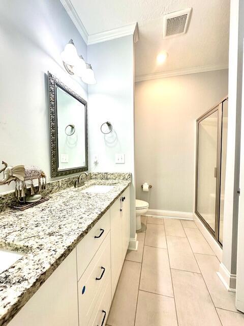 bathroom featuring tile patterned floors, an enclosed shower, toilet, vanity, and ornamental molding