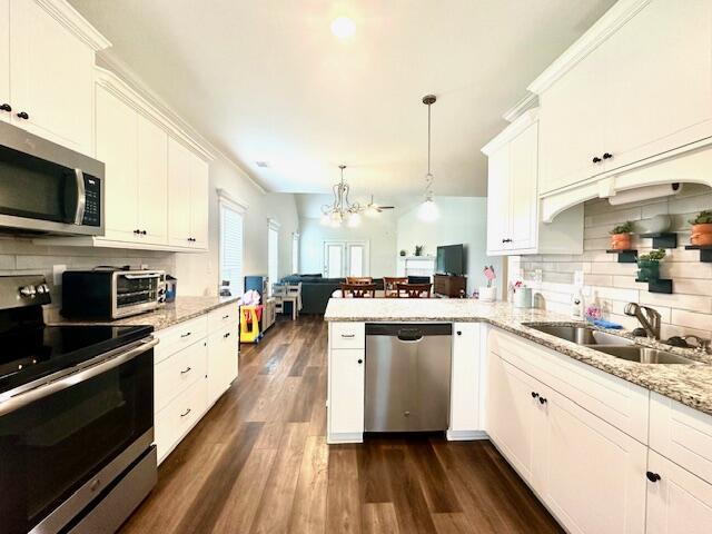 kitchen featuring stainless steel appliances, white cabinetry, hanging light fixtures, and a notable chandelier